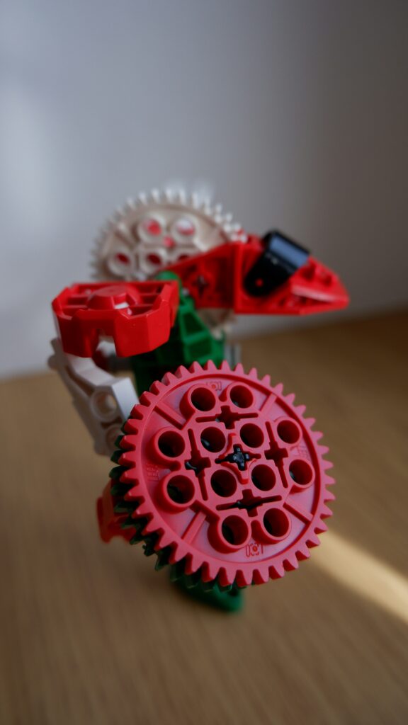 image of a red colored plastic gear.used in toys, prototypes, robots.